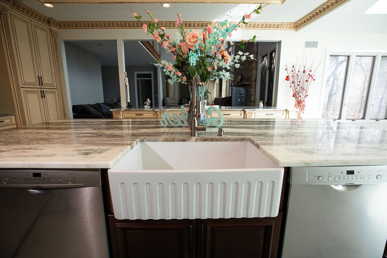 A kitchen sink with a vase of flowers on top of it.