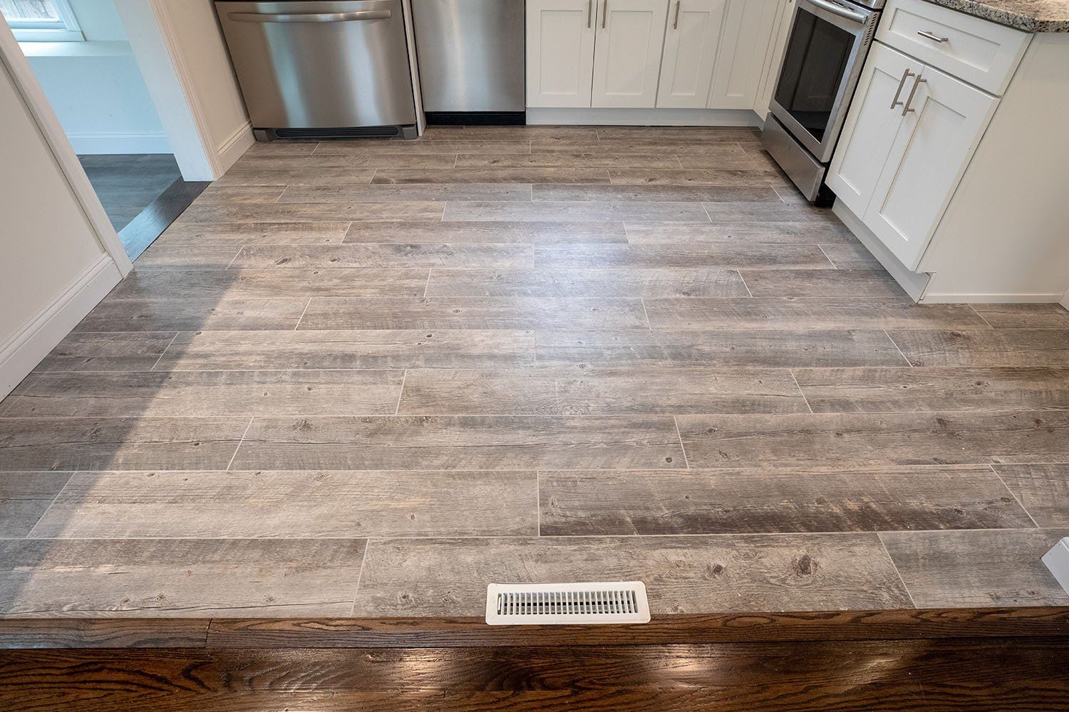 A kitchen with a wooden floor and stainless steel appliances.