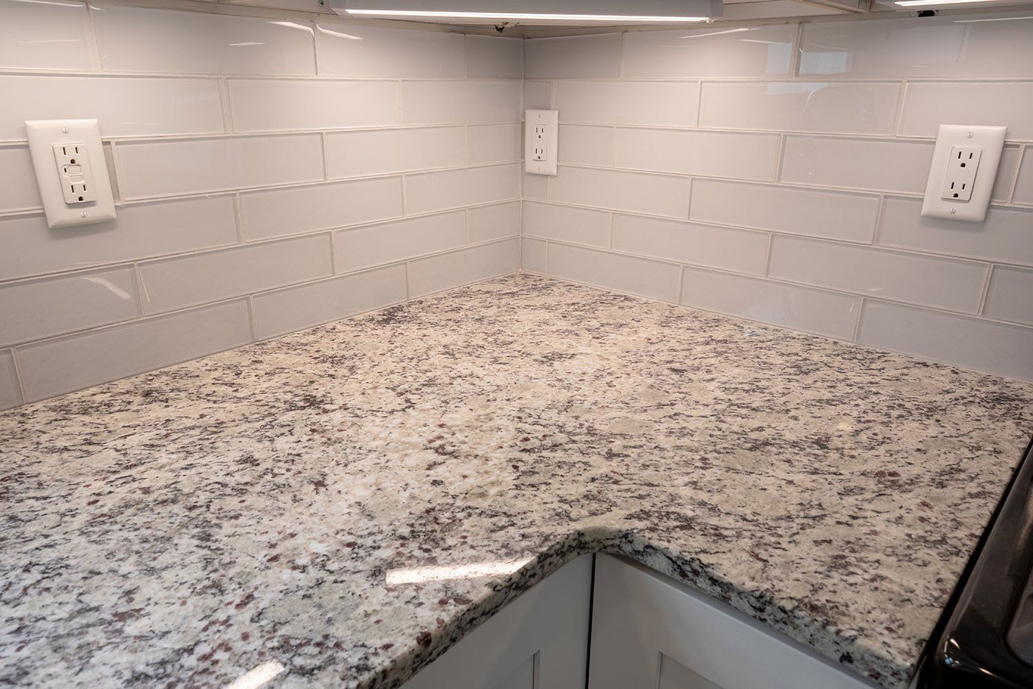 A kitchen with granite counter tops and white subway tiles.