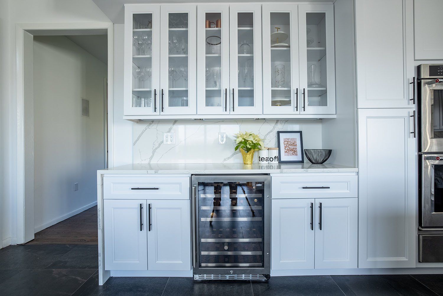 A kitchen with white cabinets , stainless steel appliances , and a wine cooler.
