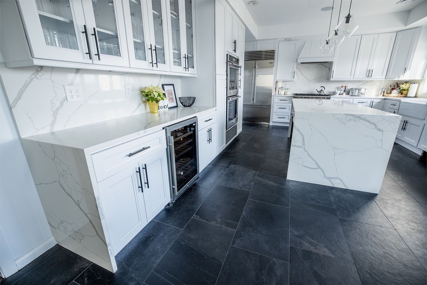 A kitchen with white cabinets and black tile floors