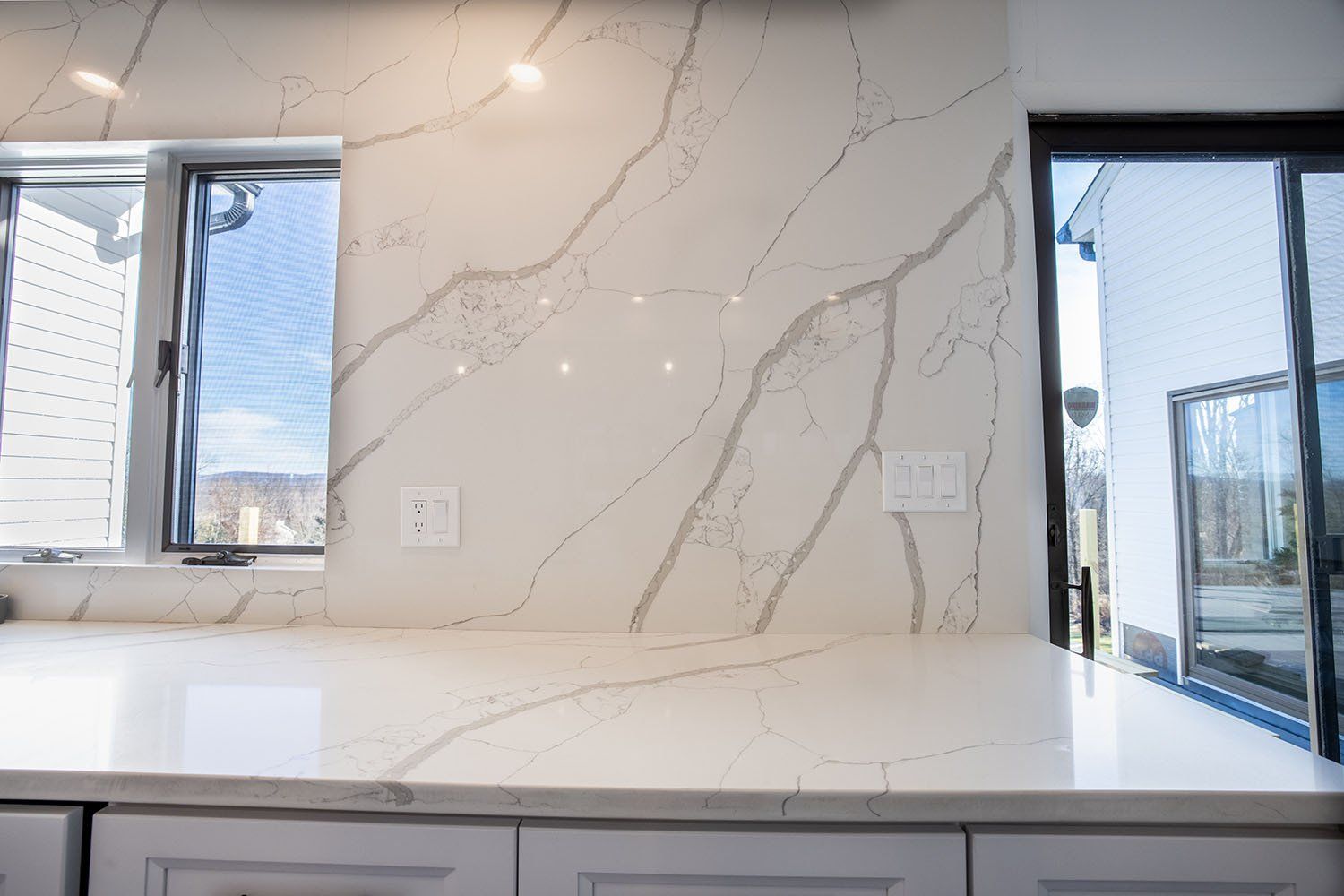 A kitchen counter with a marble counter top and a window.