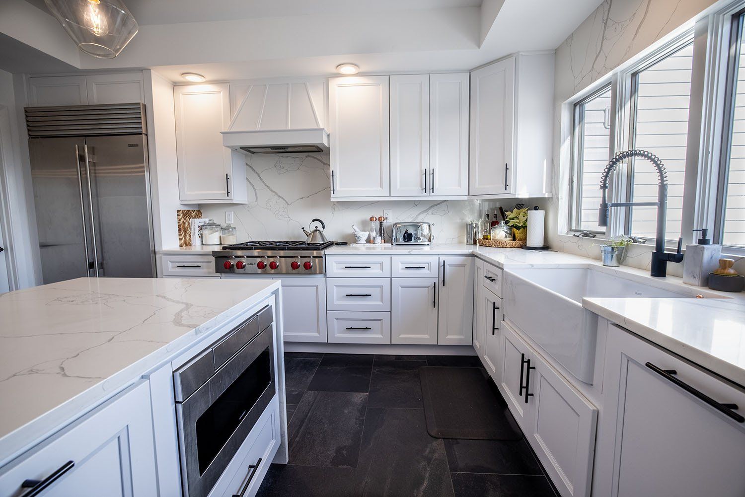 A kitchen with white cabinets , a sink , and a stove.