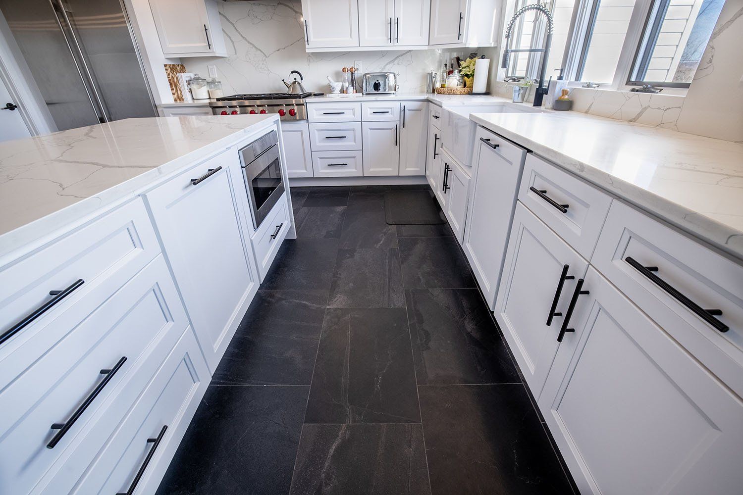 A kitchen with white cabinets and black counter tops.