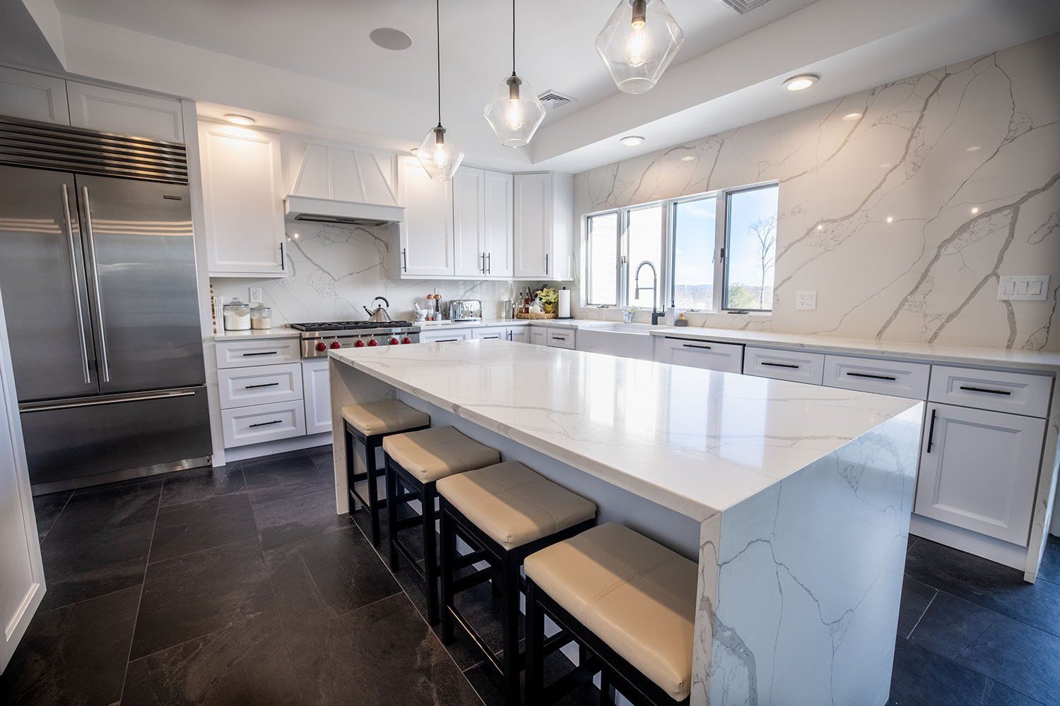 A kitchen with white cabinets , stainless steel appliances , and a large island.
