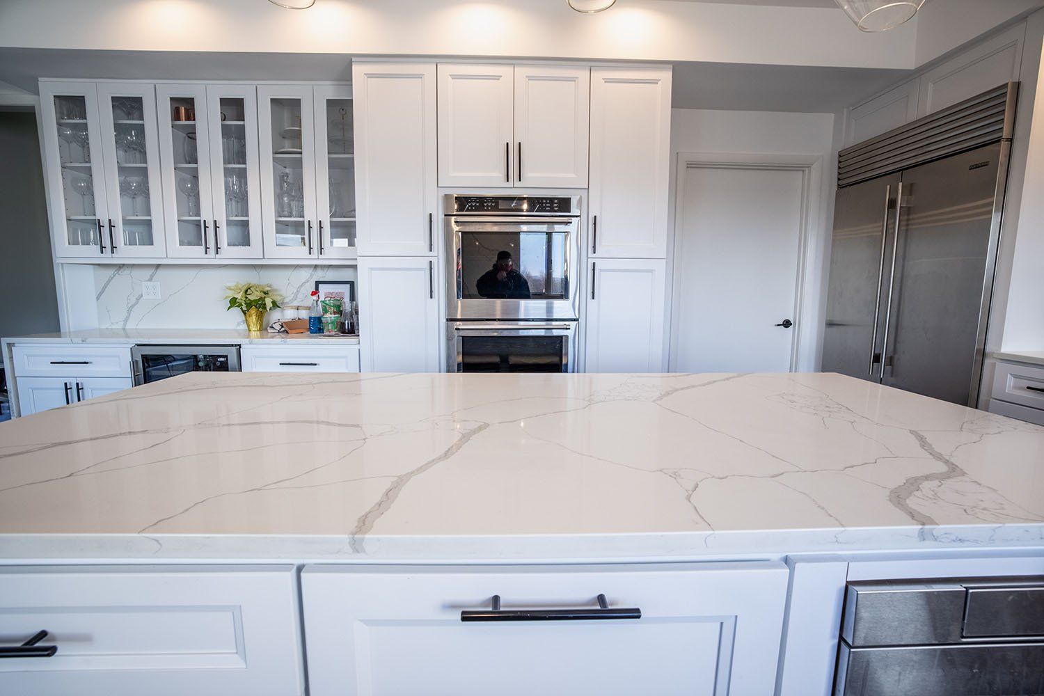 A kitchen with white cabinets , granite counter tops , stainless steel appliances and a large island.