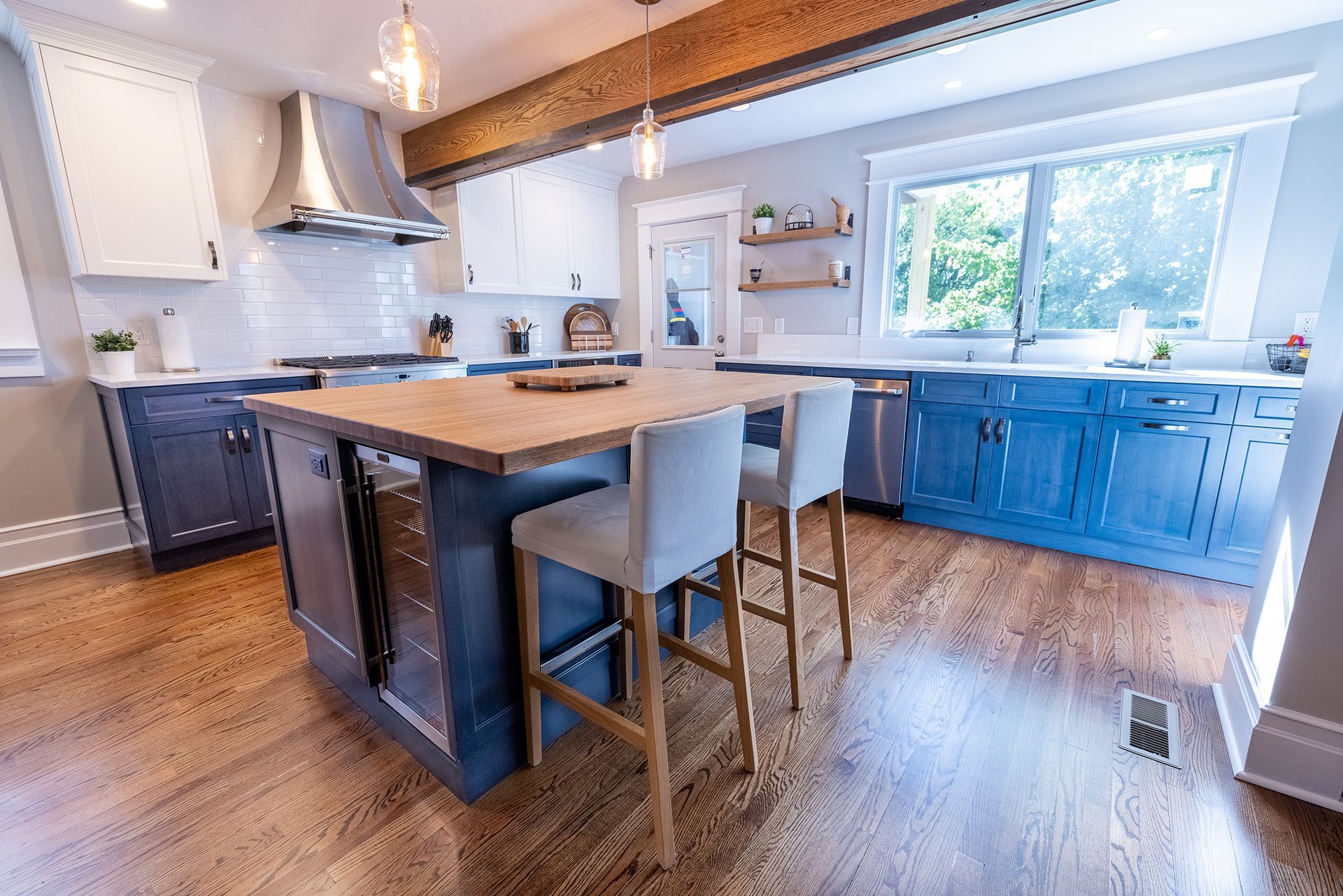 A kitchen with blue cabinets , white cabinets , hardwood floors and a large island.