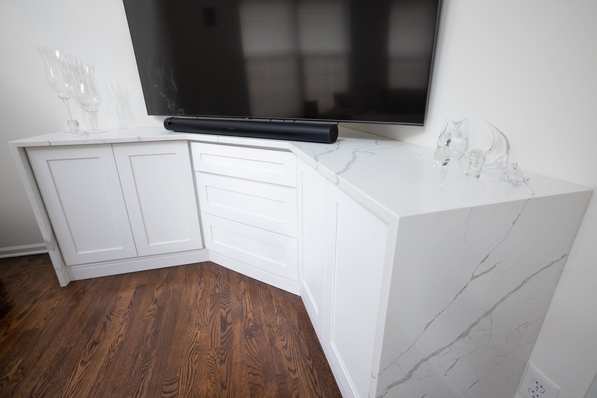 A flat screen tv is sitting on top of a corner cabinet in a living room.