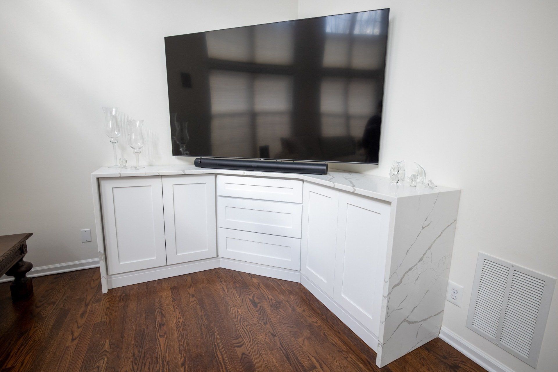 A large flat screen tv is sitting on top of a white cabinet in a living room.