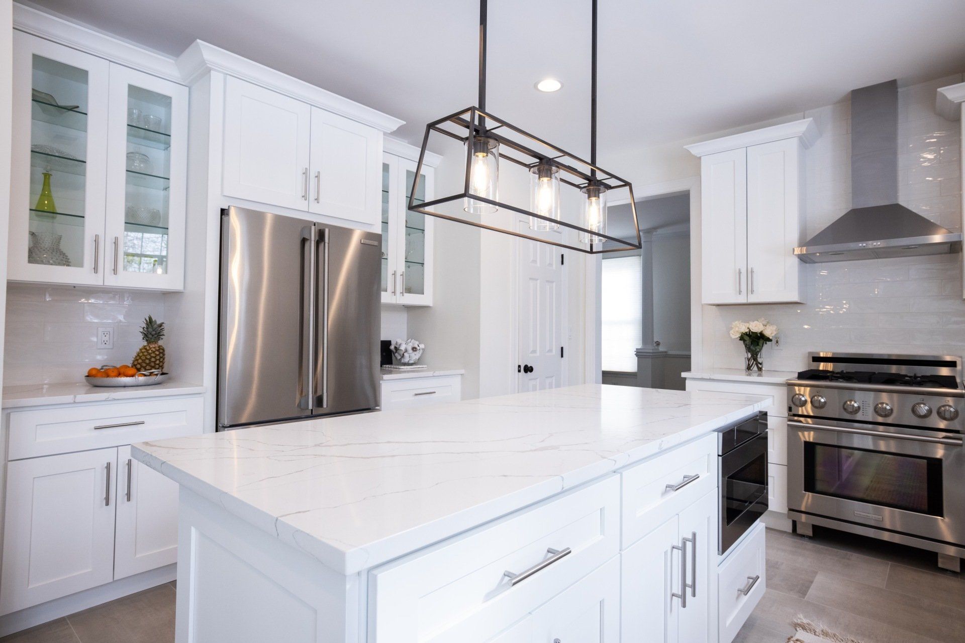 A kitchen with white cabinets , stainless steel appliances , and a large island.