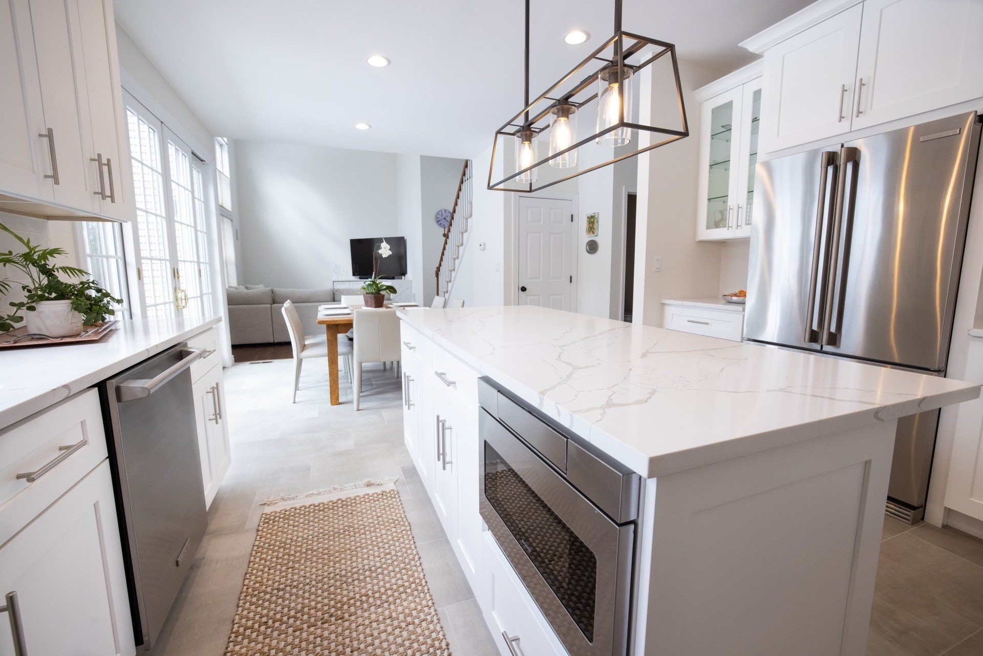 A kitchen with white cabinets , stainless steel appliances , and a large island.