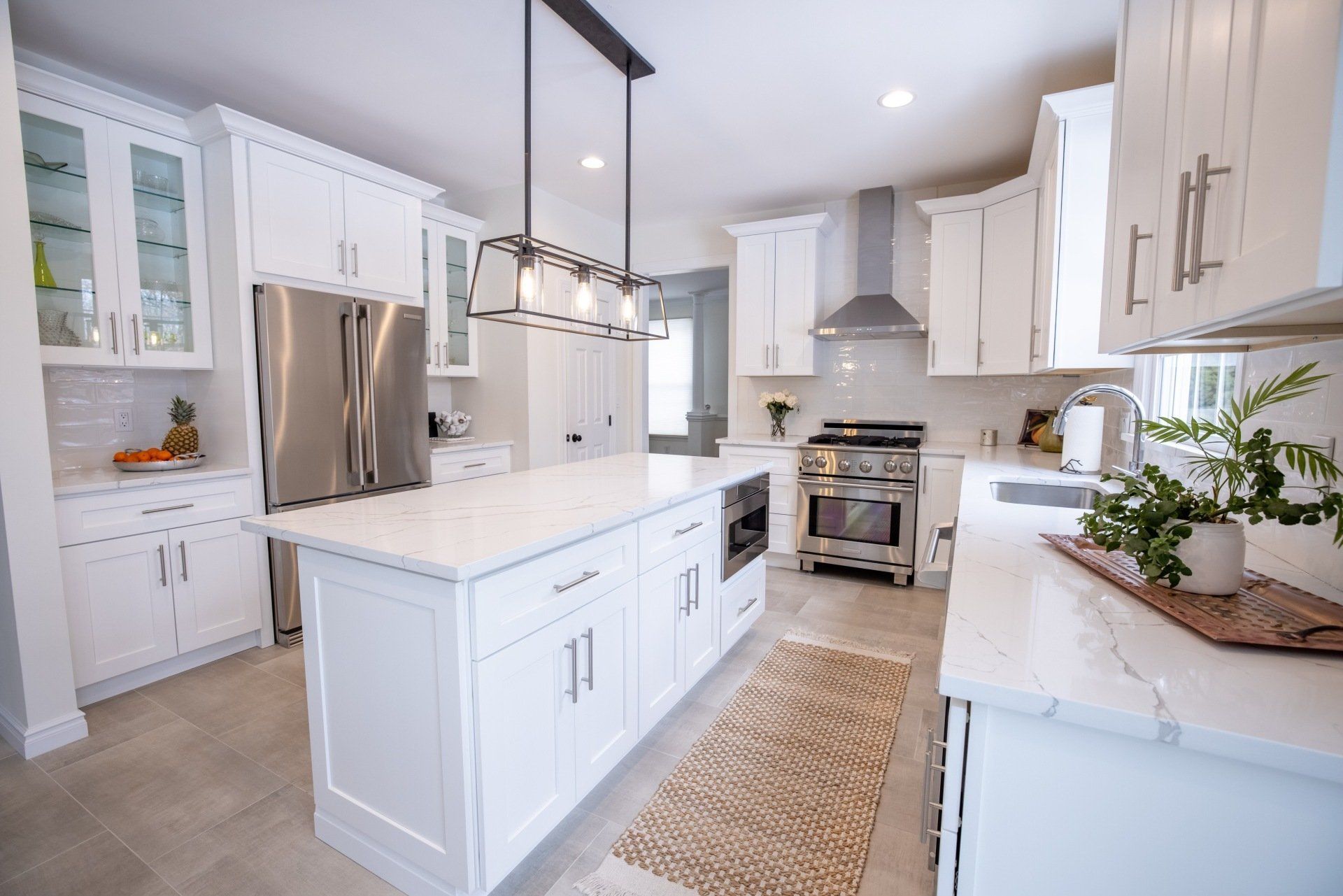 A kitchen with white cabinets , stainless steel appliances , and a large island.
