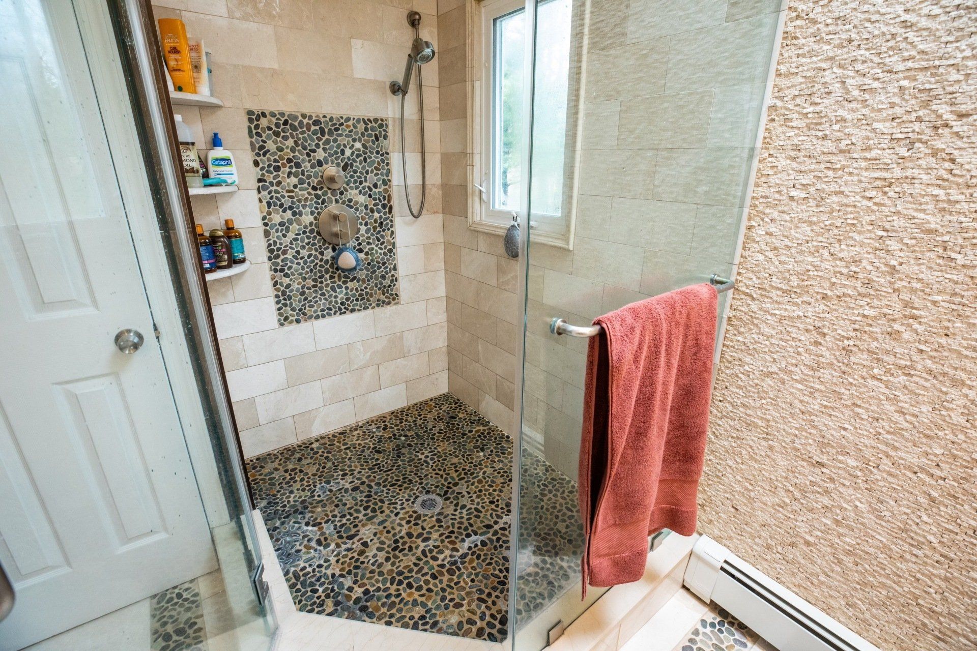 A bathroom with a walk in shower and a window.