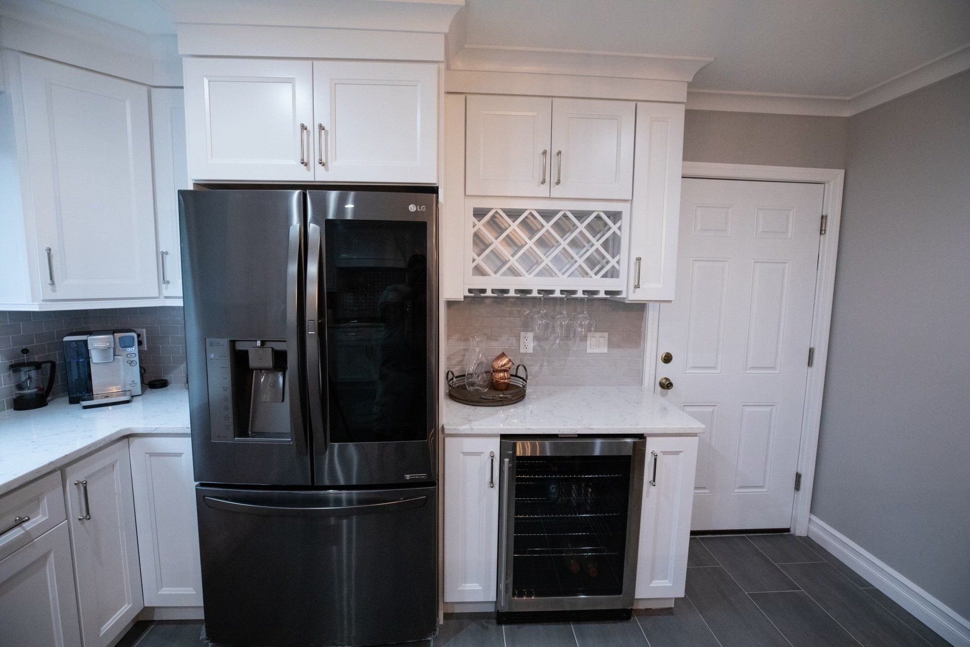 A kitchen with white cabinets and a stainless steel refrigerator
