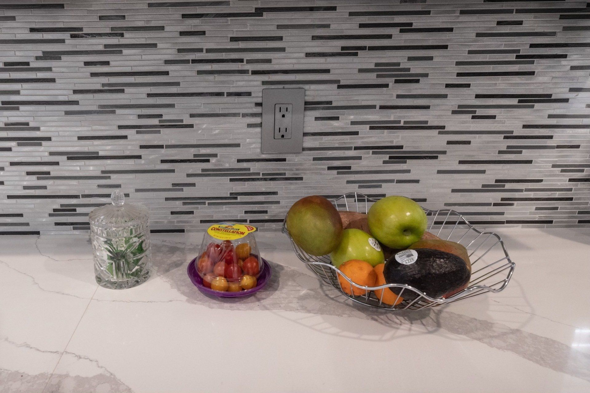 A bowl of fruit is sitting on a counter in a kitchen.