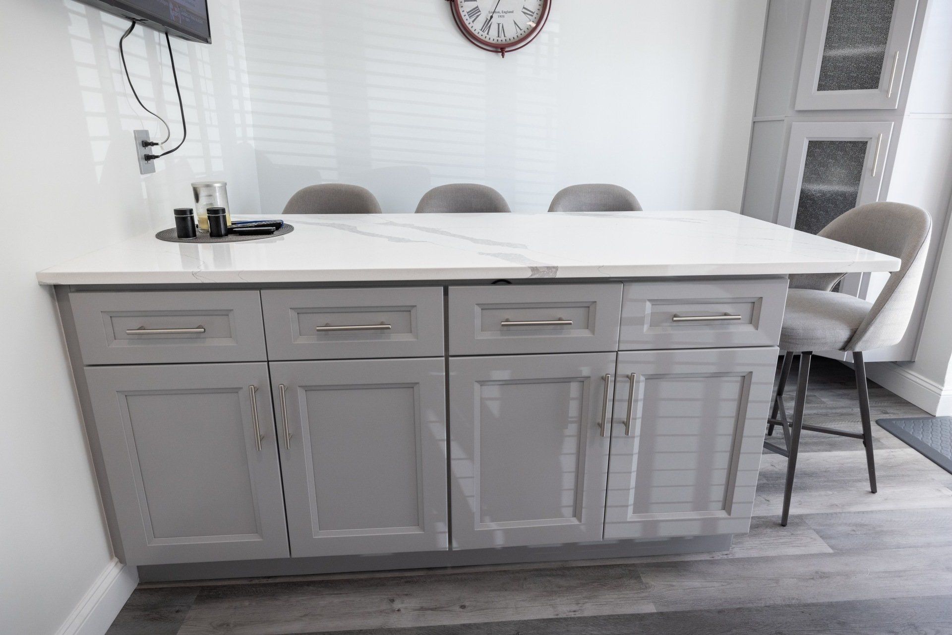 A kitchen with gray cabinets and a white counter top.