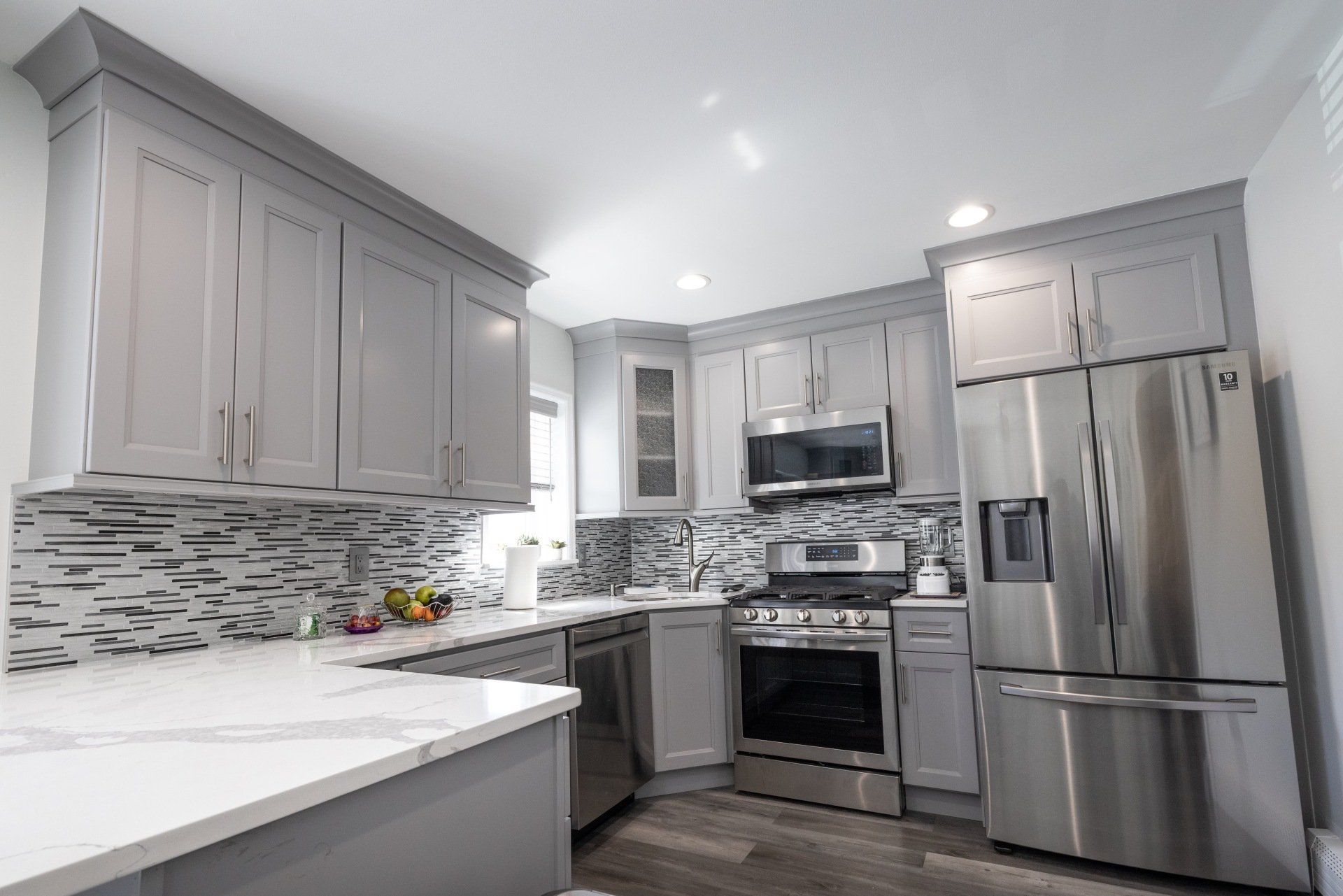 A kitchen with gray cabinets and stainless steel appliances.