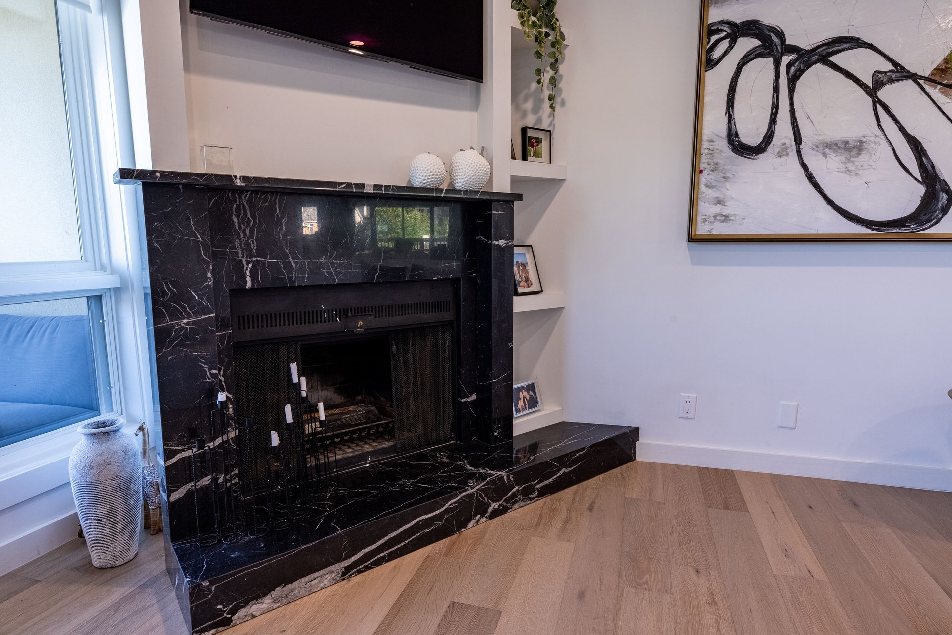 A living room with a fireplace and a painting on the wall.