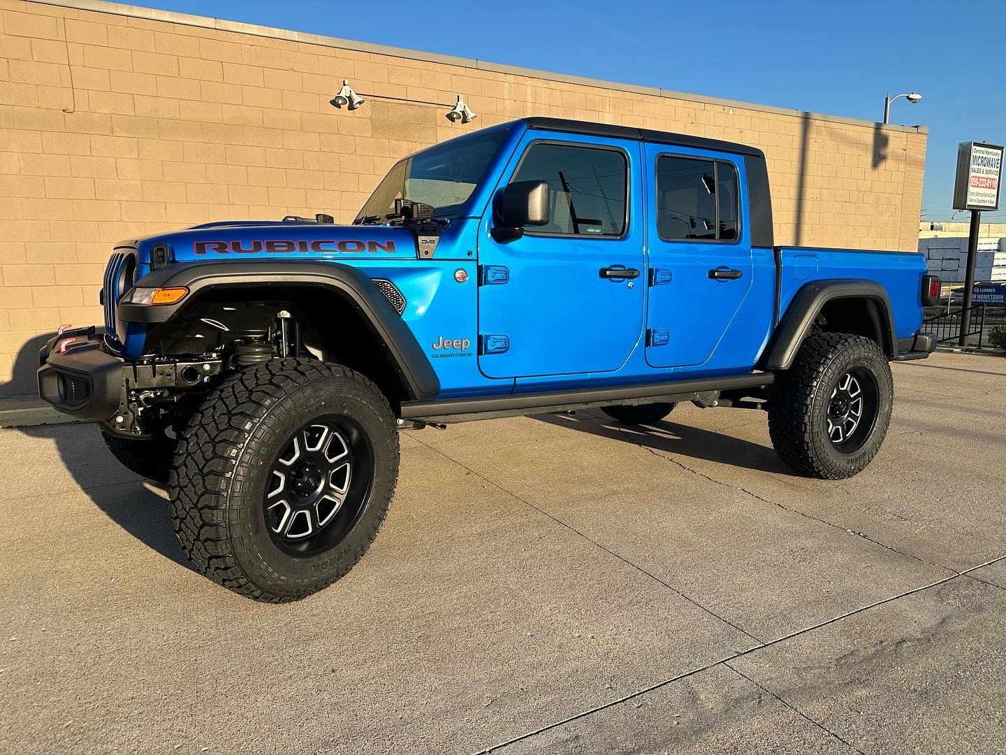 A blue Jeep is parked in front of a brick building.
