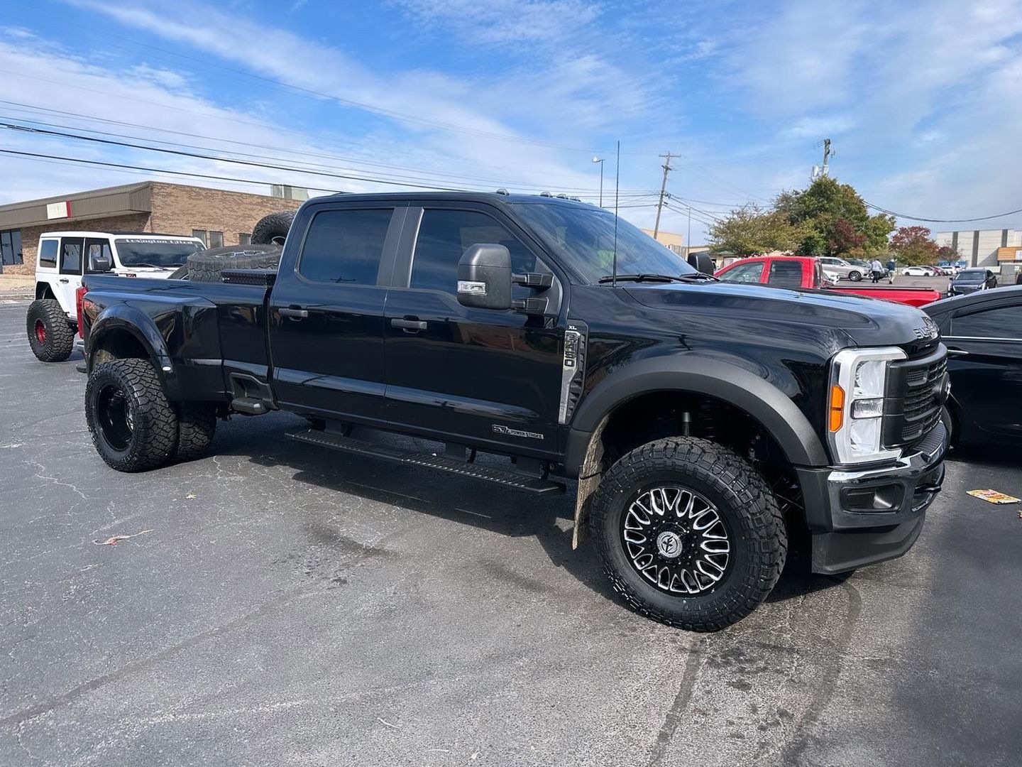 A black Ford f350 super duty pickup truck is parked in a parking lot.