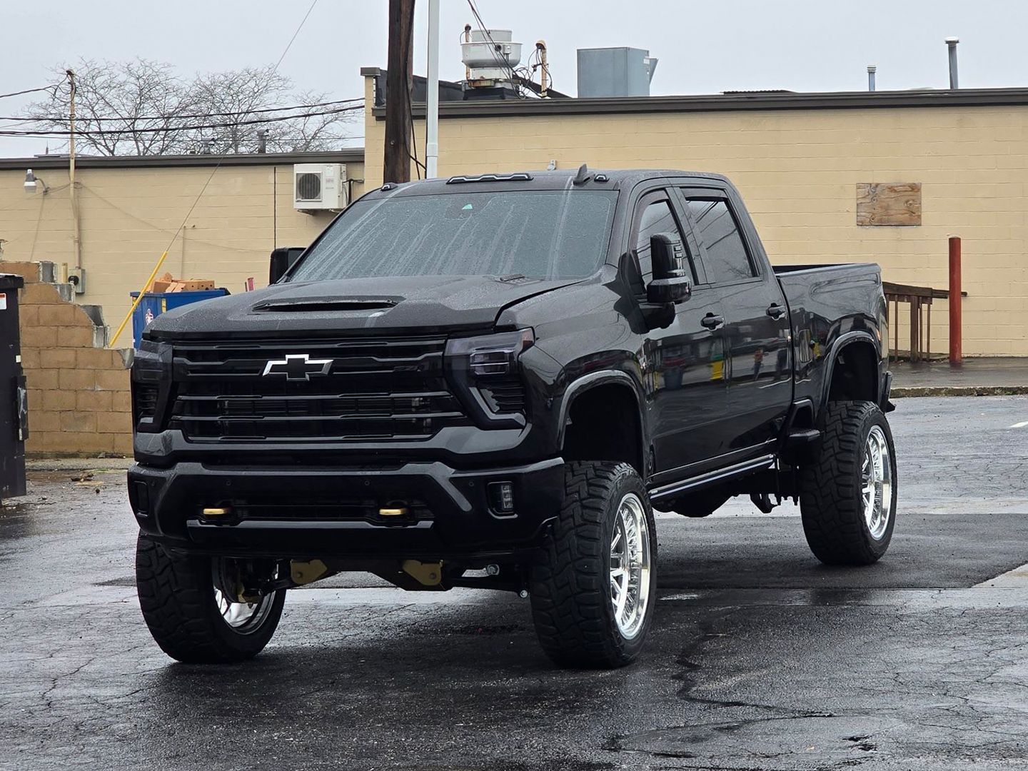 A black truck is parked in a parking lot in front of a building.