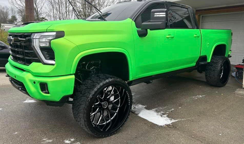 A neon green truck is parked in front of a garage.