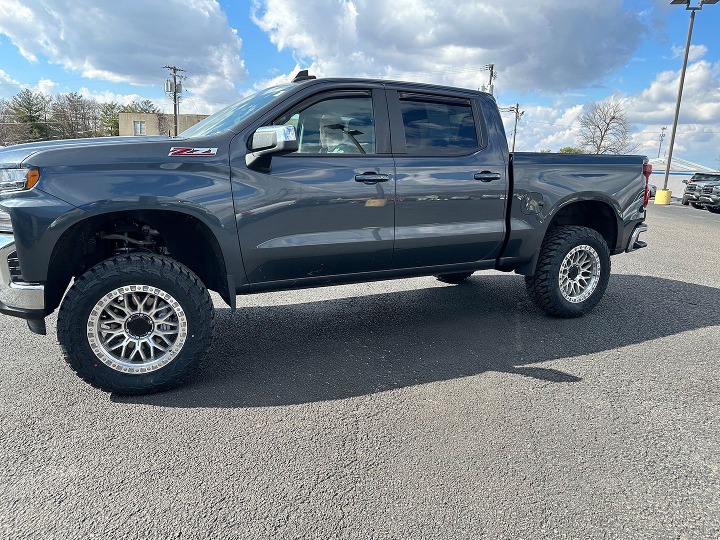 A gray truck is parked in a gravel lot.