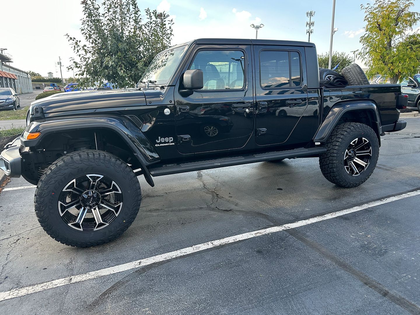 A black Jeep gladiator is parked in a parking lot.