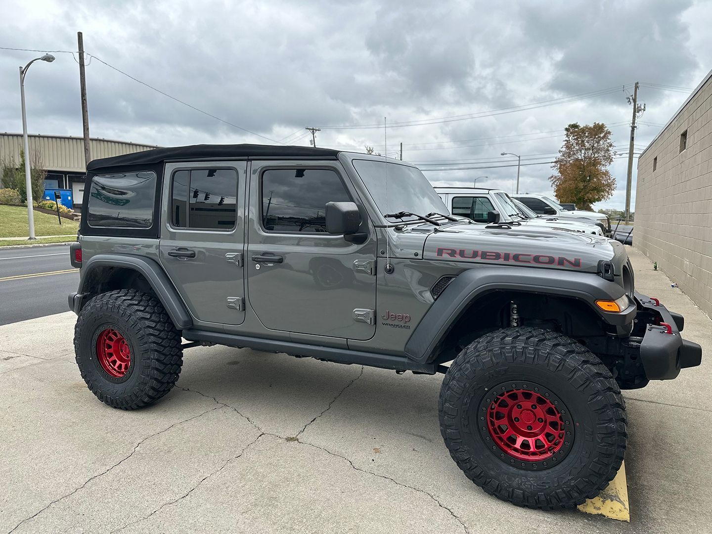 A Jeep Wrangler is parked on the side of the road in front of a building.