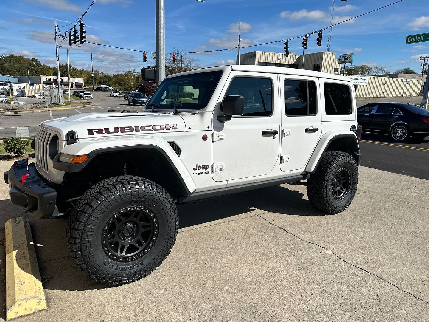 A white Jeep Wrangler Rubicon is parked on the side of the road.
