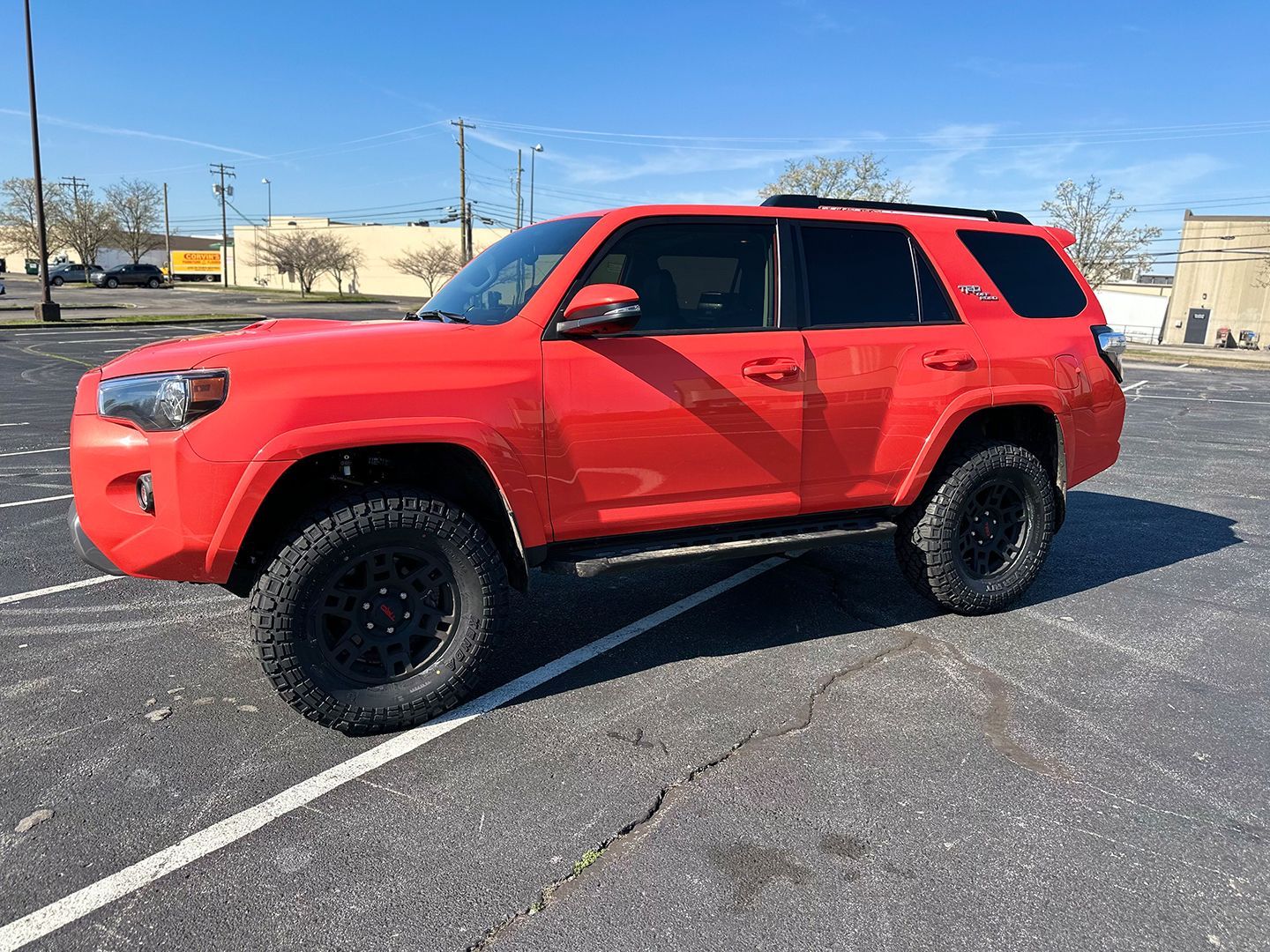 A red Toyota 4runner is parked in a parking lot.
