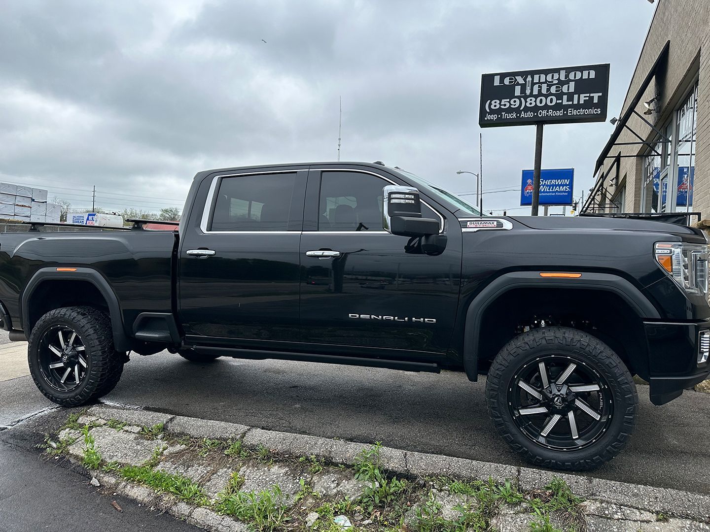 A black pickup truck is parked on the side of the road in front of a building.