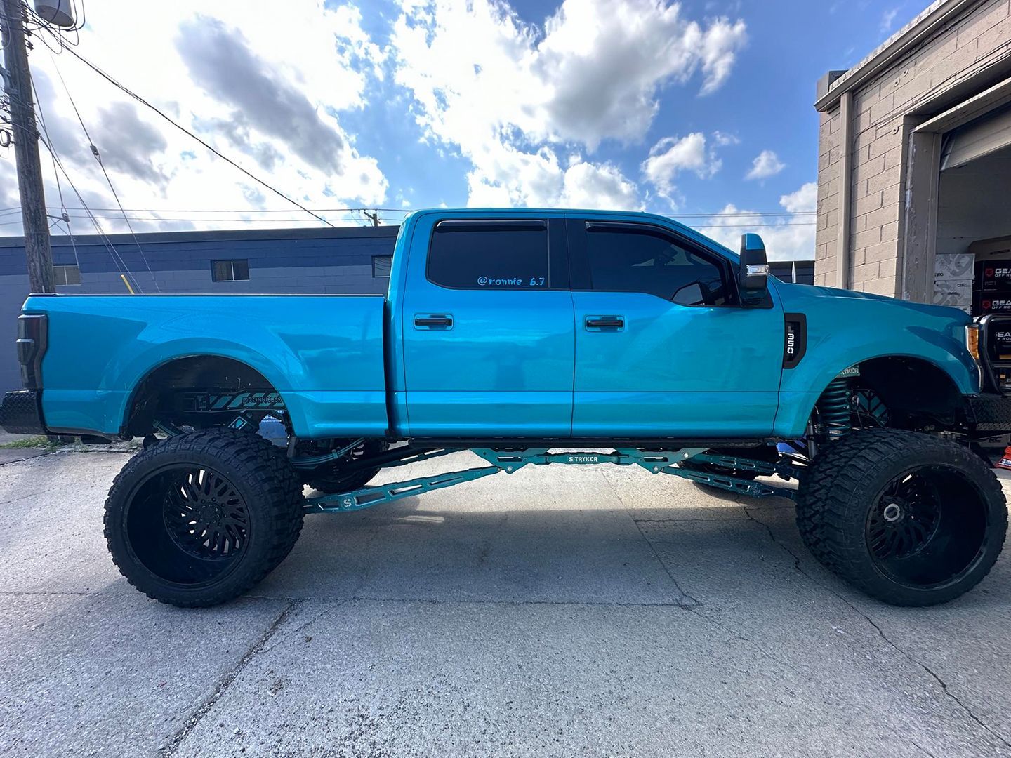 A blue truck with black wheels is parked in front of a building.