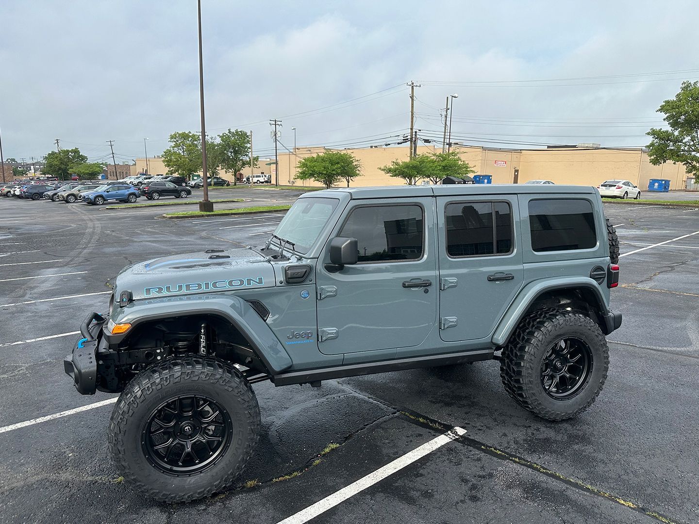A gray Jeep is parked in a parking lot.