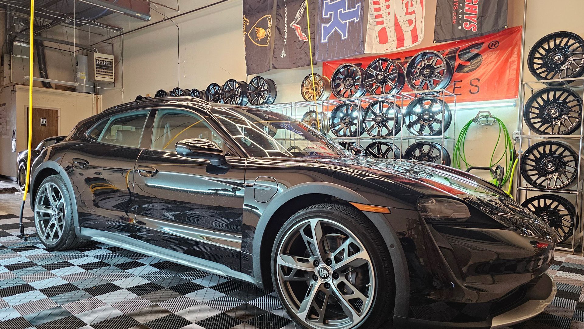 A black Porsche Taycan is parked in a garage.