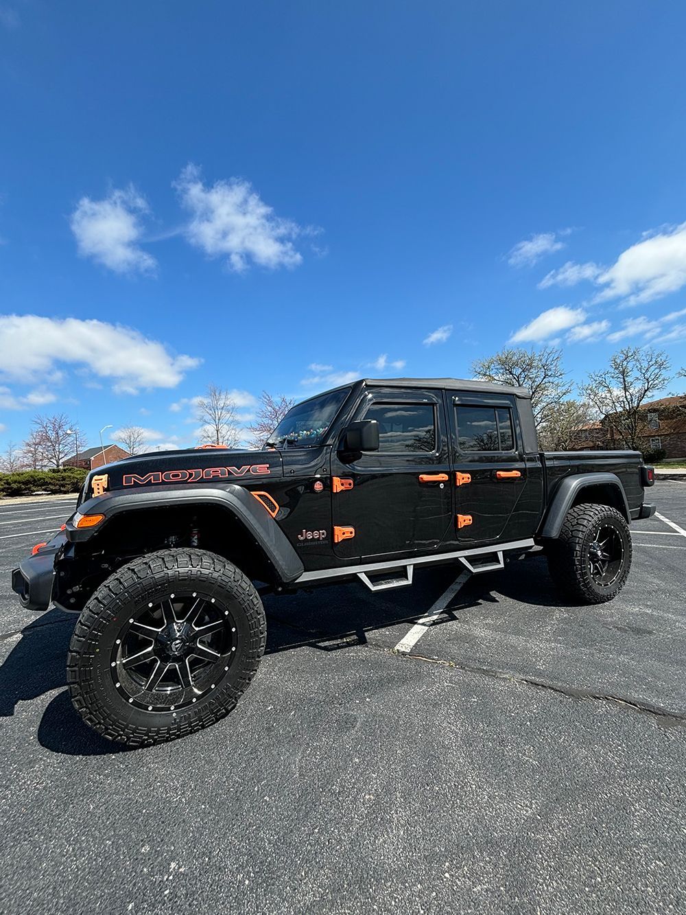 A black Jeep gladiator is parked in a parking lot.