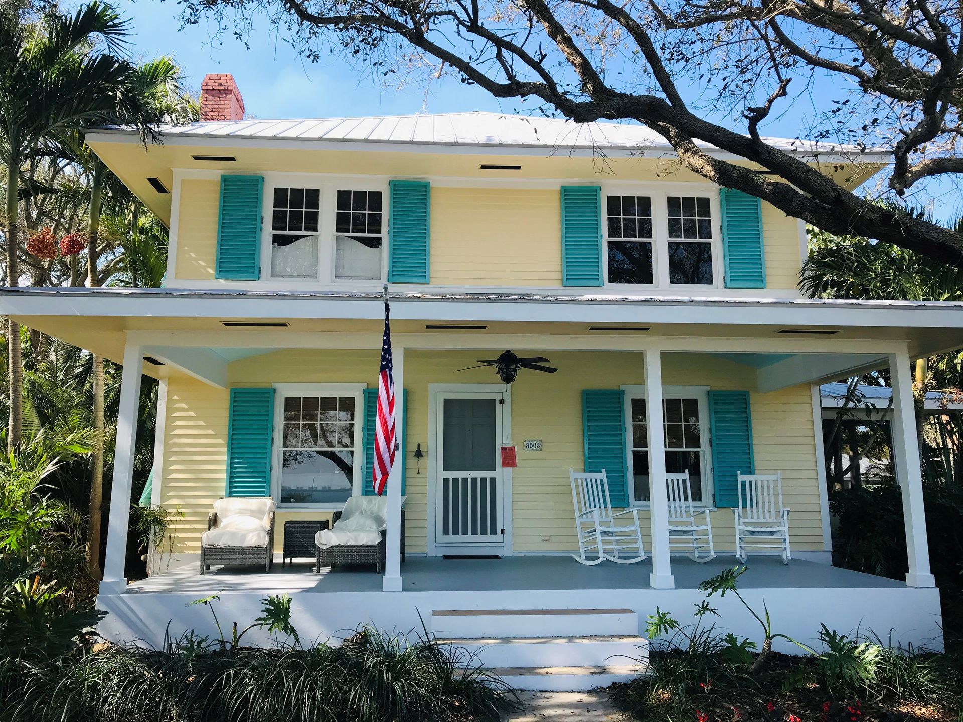 A yellow house with blue shutters and a porch