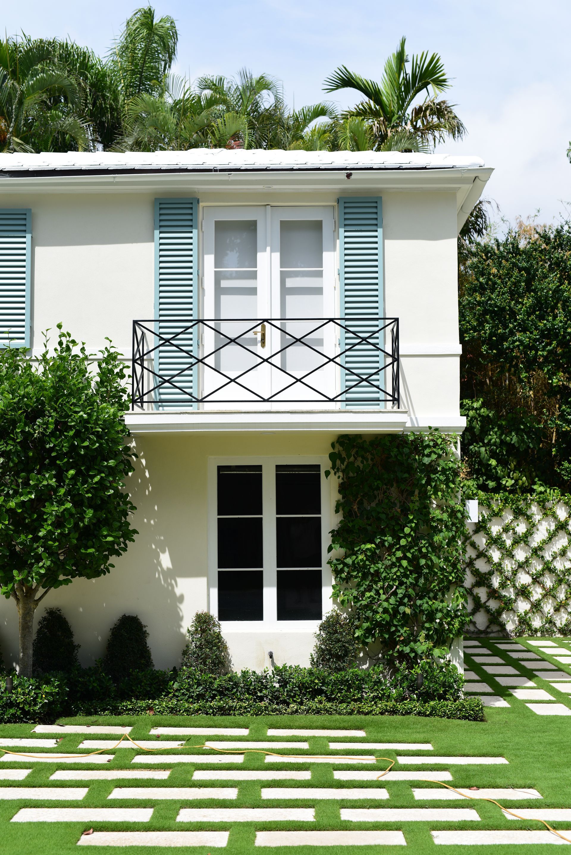 A white house with blue shutters and a balcony