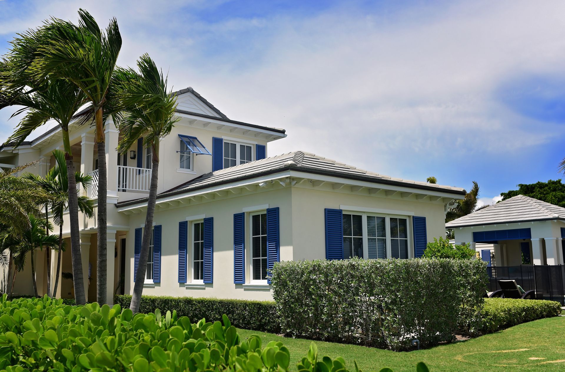 A large white house with blue shutters and palm trees