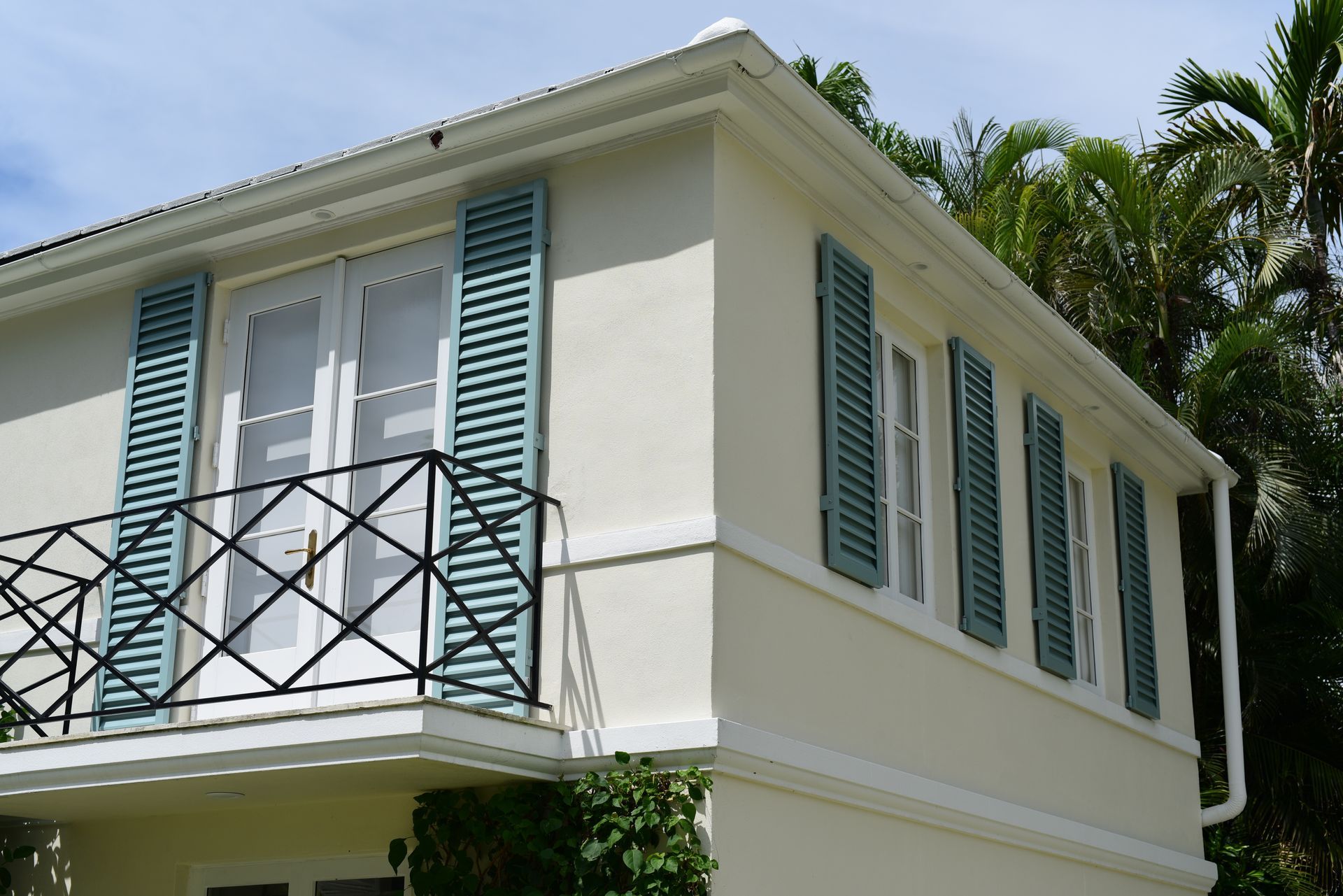 A white house with blue shutters and a balcony