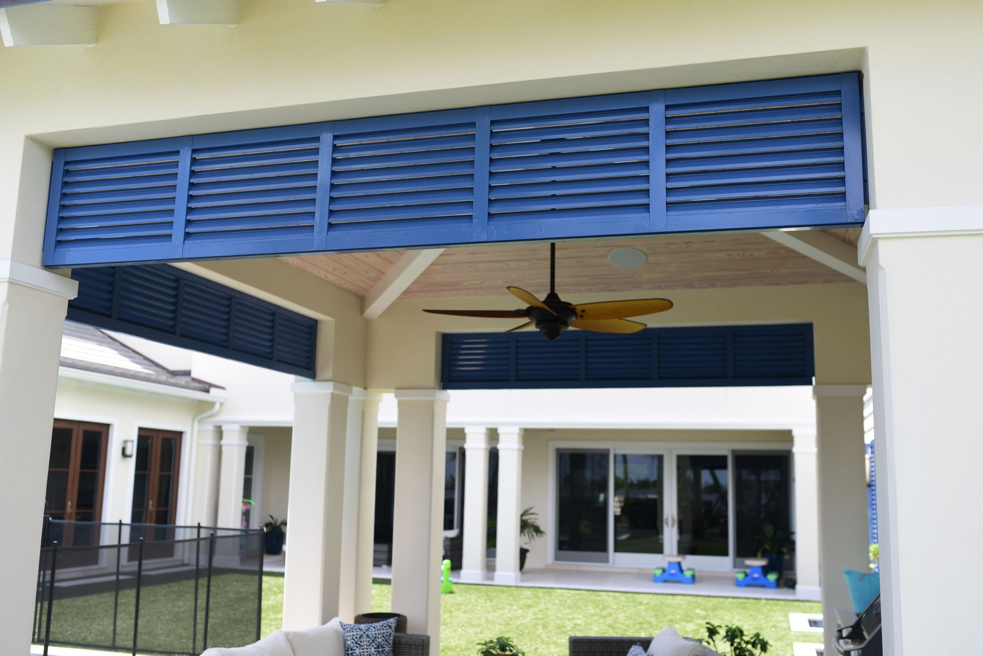A patio with a ceiling fan and blue shutters