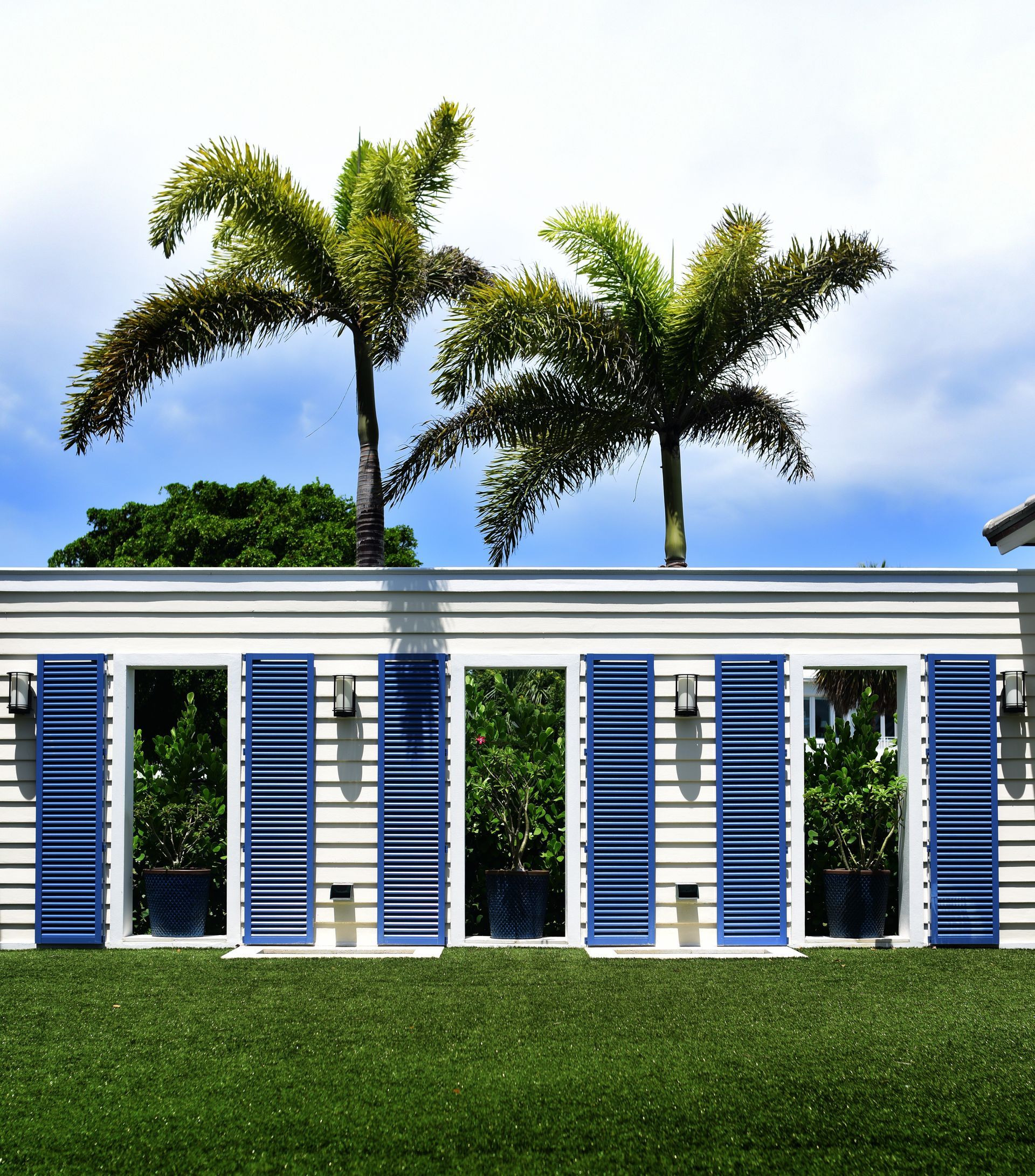 A white house with blue shutters and palm trees in the background