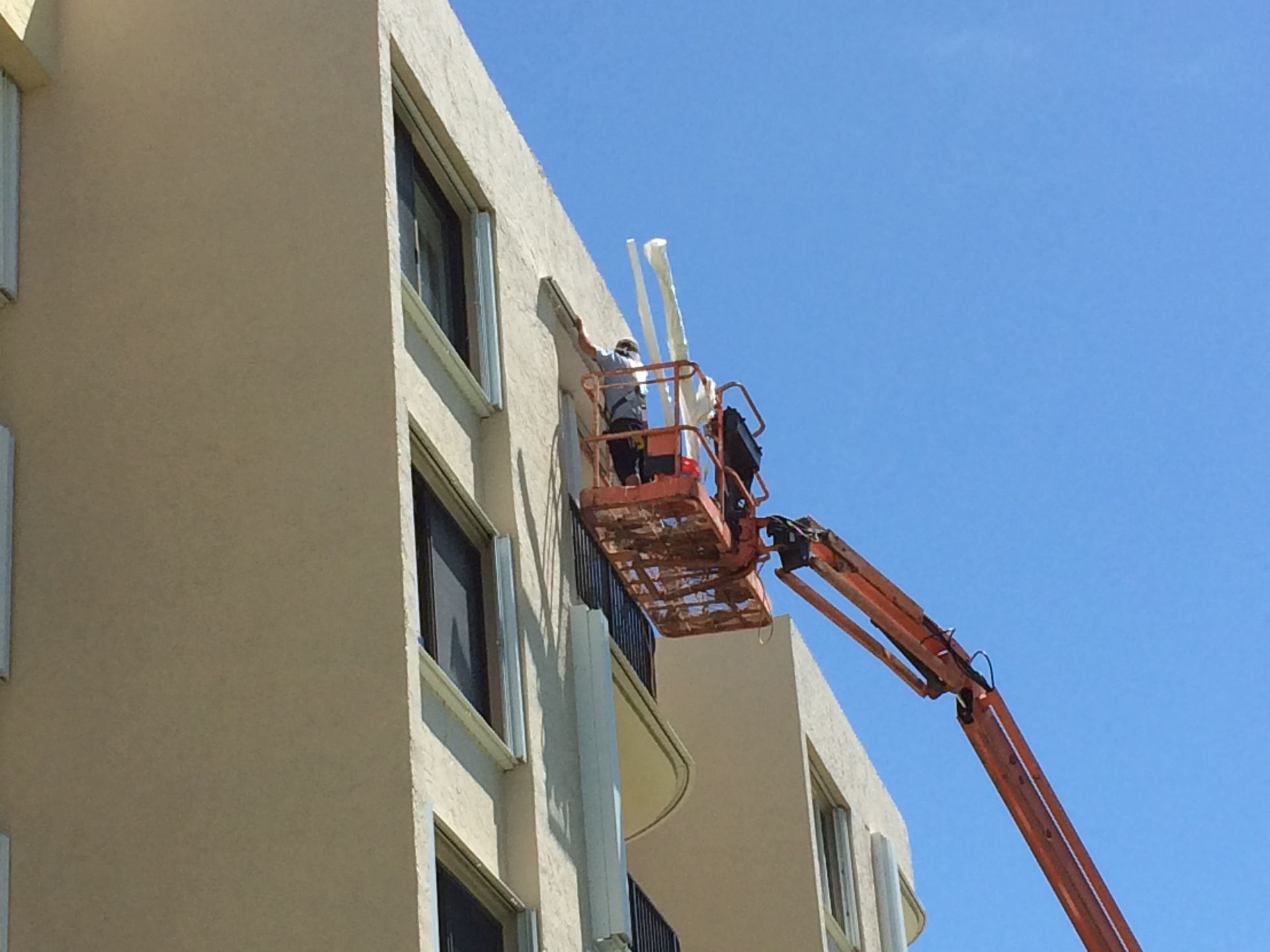 A man in a crane is painting the side of a building