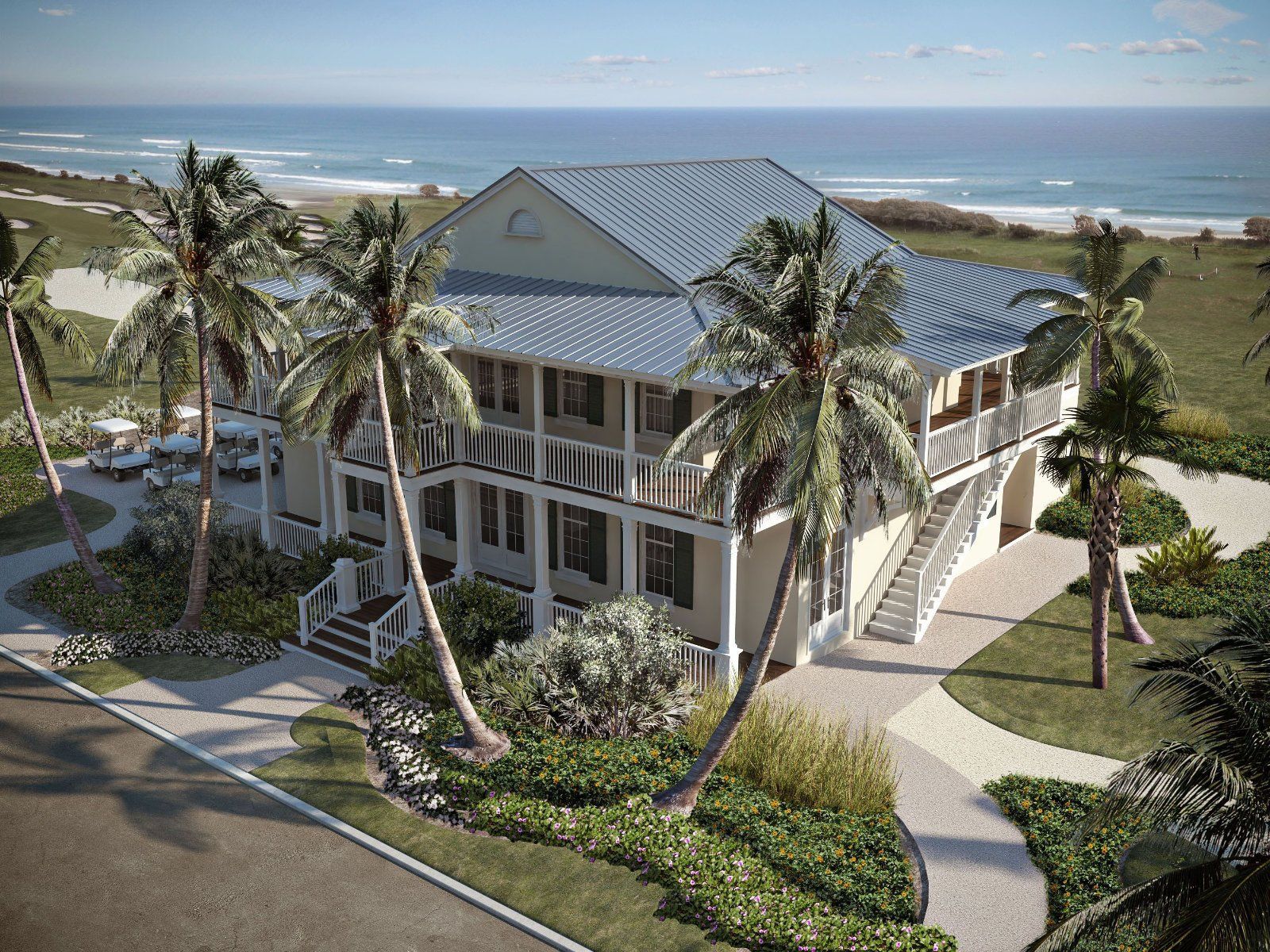 An aerial view of a large house with palm trees in front of the ocean.