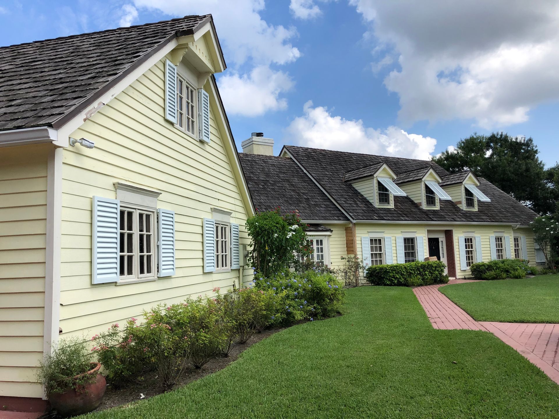 A yellow house with white shutters on the windows