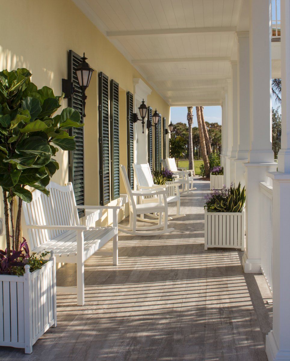 A porch with white chairs and planters on it