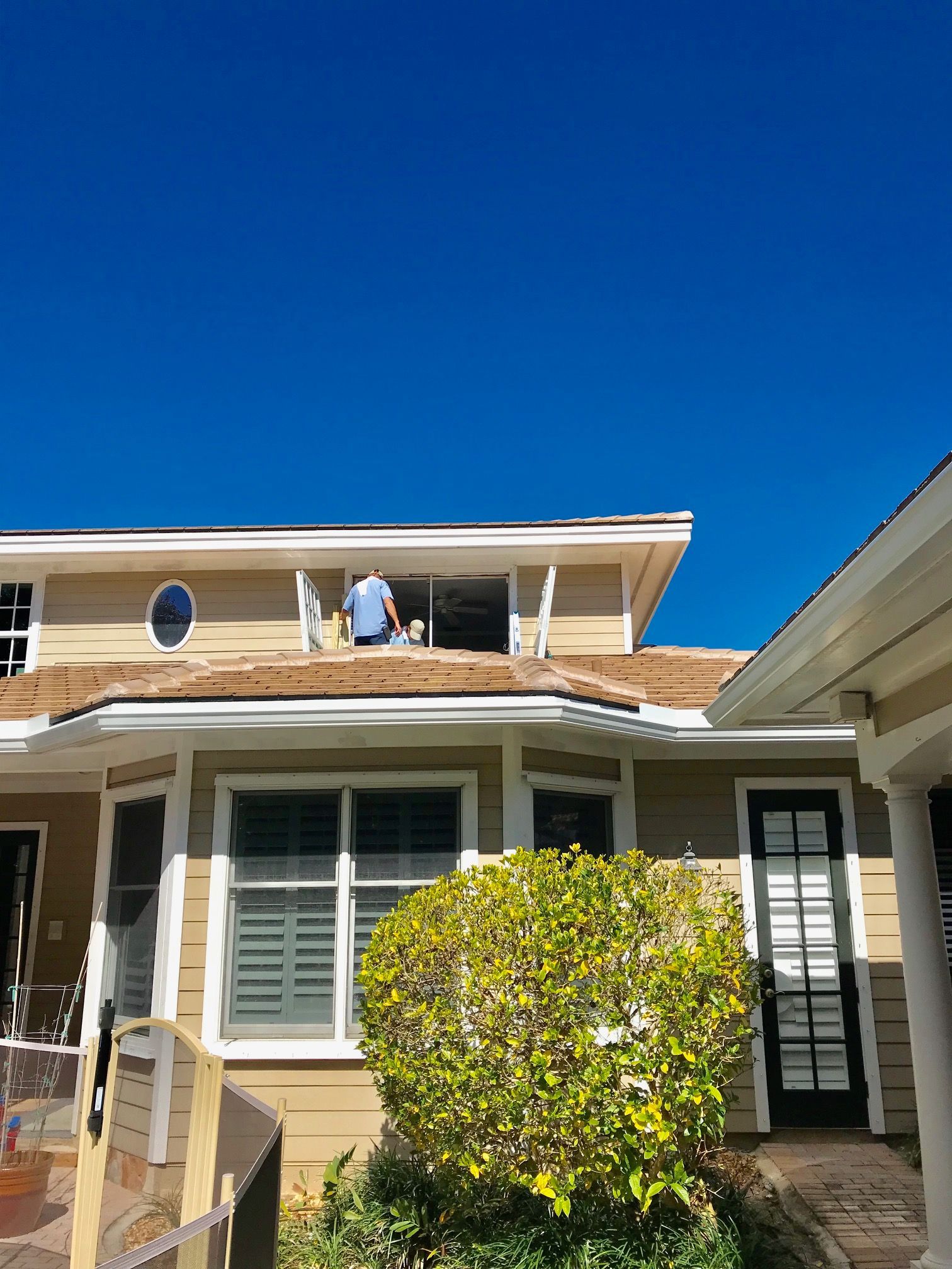 A man is working on the roof of a house on a sunny day.