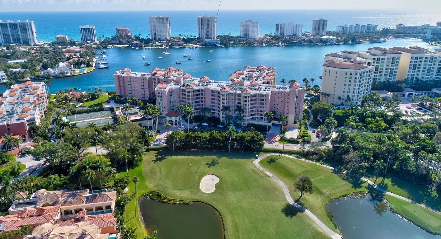 An aerial view of a golf course surrounded by buildings and a body of water.