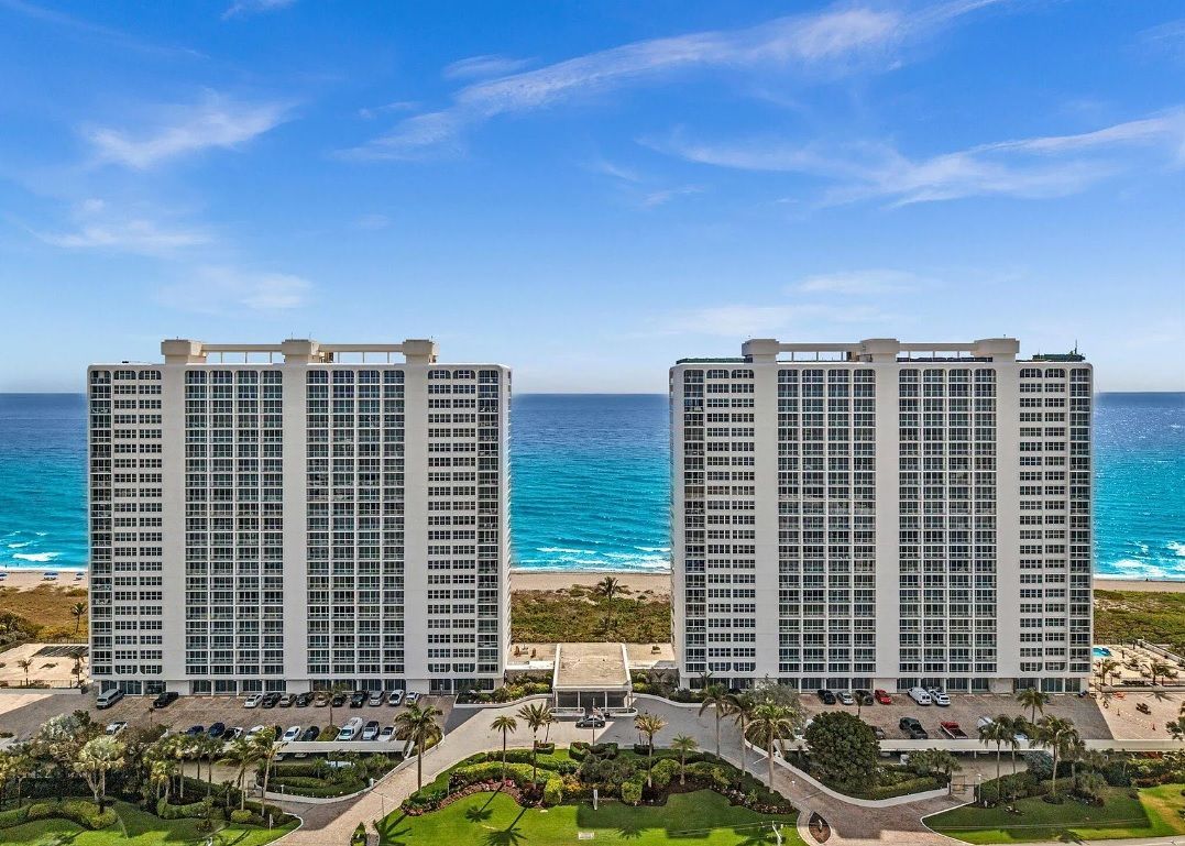 An aerial view of two tall buildings next to the ocean.