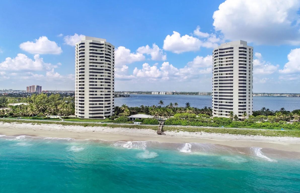 An aerial view of a beach with two tall buildings in the background.